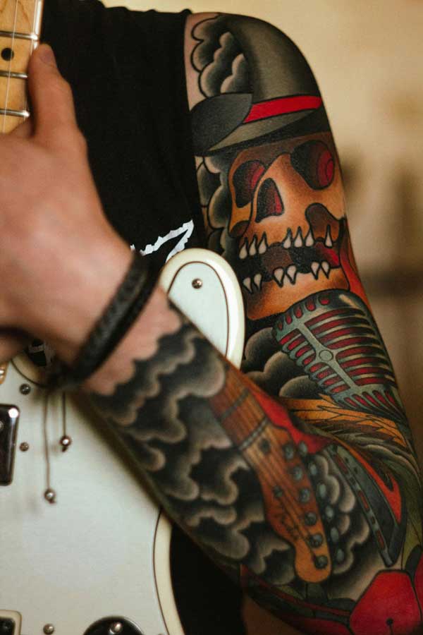 tattooed arm holding a guitar